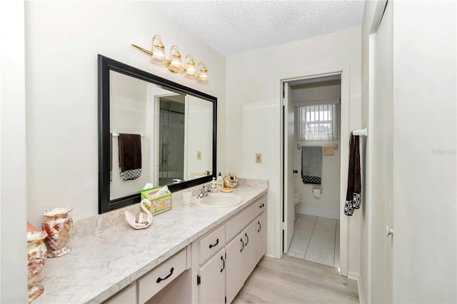 bathroom featuring vanity, a textured ceiling, hardwood / wood-style flooring, and toilet