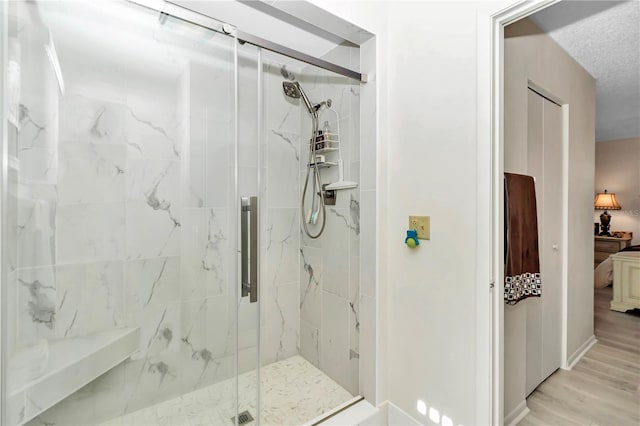 bathroom with a shower with shower door, wood-type flooring, and a textured ceiling