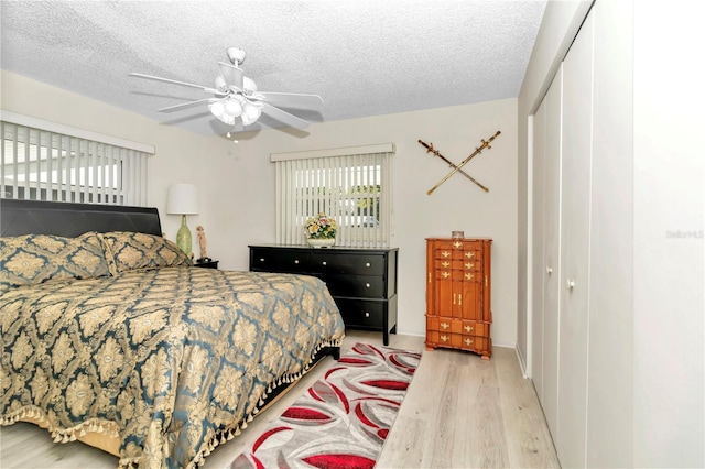 bedroom with ceiling fan, a closet, a textured ceiling, and light wood-type flooring