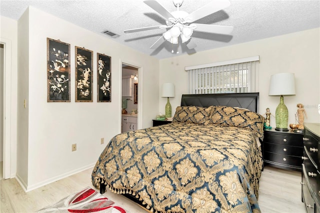 bedroom featuring a textured ceiling, ensuite bathroom, light hardwood / wood-style flooring, and ceiling fan