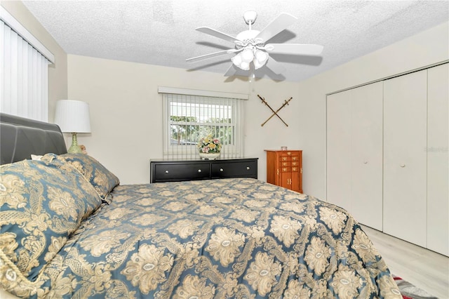 bedroom featuring a closet, a textured ceiling, light hardwood / wood-style floors, and ceiling fan