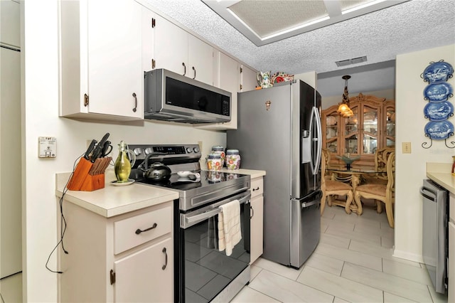 kitchen featuring white cabinets, pendant lighting, stainless steel appliances, and a textured ceiling