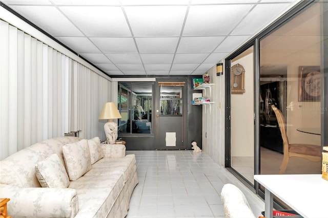 living room with a paneled ceiling and light tile patterned flooring