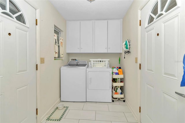 clothes washing area with cabinets, a textured ceiling, washer and clothes dryer, and light tile patterned flooring