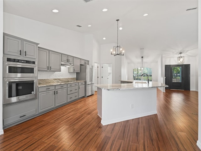 kitchen featuring gray cabinetry, a spacious island, stainless steel appliances, and dark hardwood / wood-style floors