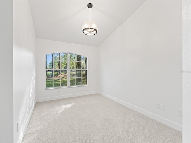 empty room featuring carpet, lofted ceiling, and a chandelier