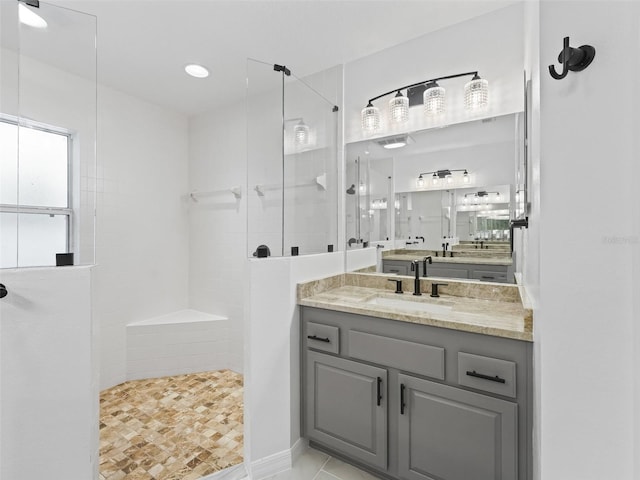 bathroom with a tile shower and vanity