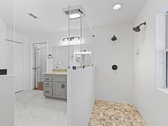 bathroom featuring tiled shower and vanity