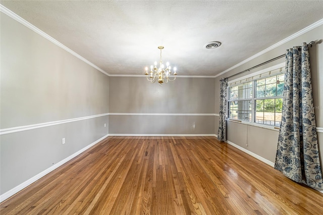 spare room with ornamental molding, wood-type flooring, a textured ceiling, and a notable chandelier