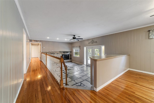 hall with crown molding, light hardwood / wood-style flooring, and wooden walls