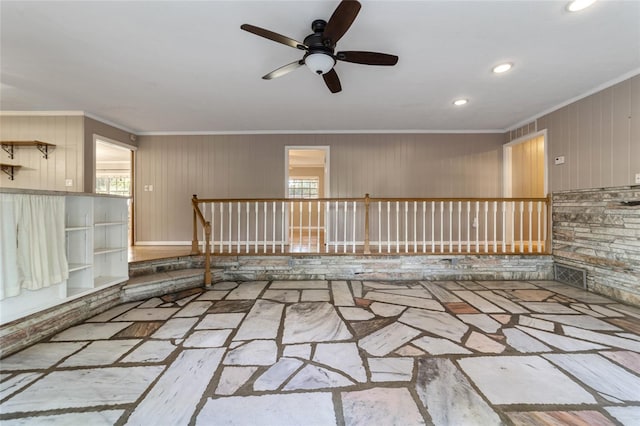 spare room featuring ceiling fan, wood walls, and ornamental molding