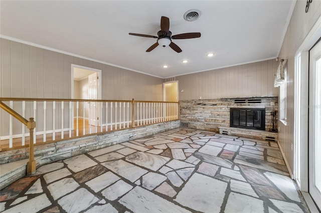 unfurnished living room featuring ceiling fan, ornamental molding, and wooden walls