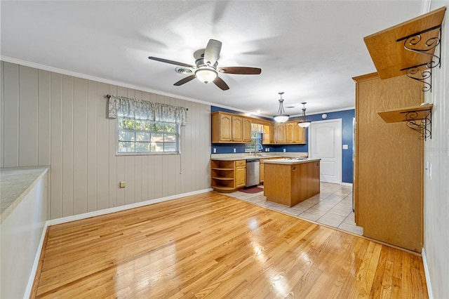 kitchen with stainless steel dishwasher, light hardwood / wood-style floors, decorative light fixtures, a kitchen island, and ornamental molding