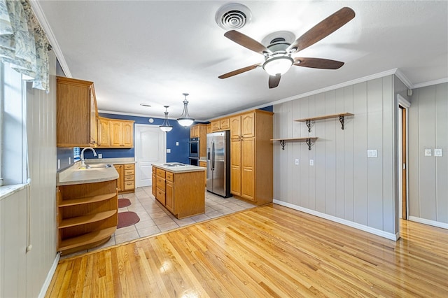 kitchen with a center island, ceiling fan, light wood-type flooring, ornamental molding, and stainless steel appliances