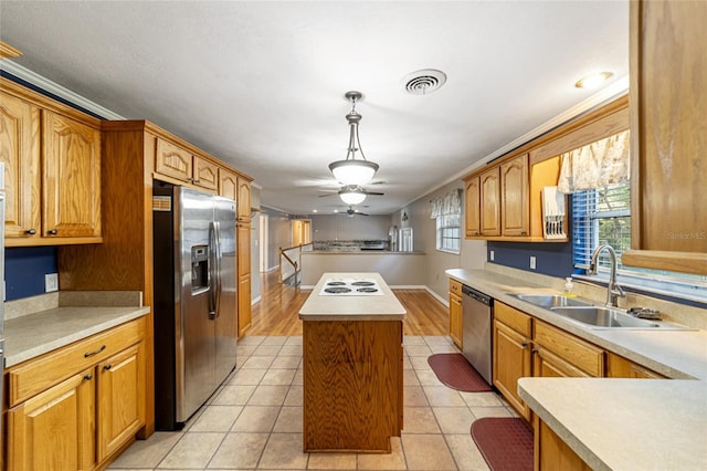 kitchen with stainless steel appliances, sink, light hardwood / wood-style floors, a kitchen island, and hanging light fixtures