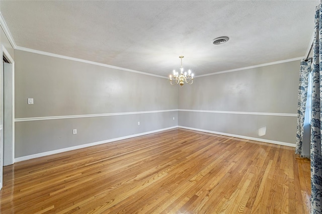 empty room with a chandelier, a textured ceiling, light wood-type flooring, and ornamental molding