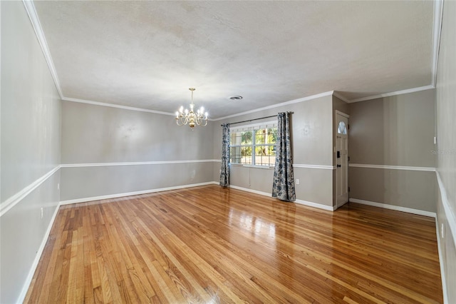 empty room with crown molding, a chandelier, a textured ceiling, and hardwood / wood-style flooring