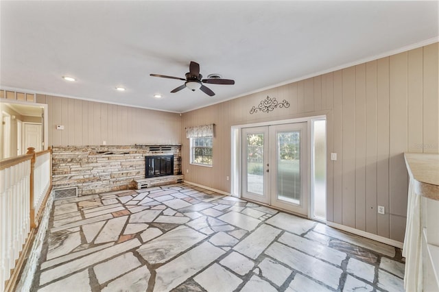 unfurnished living room with ceiling fan, wood walls, and crown molding