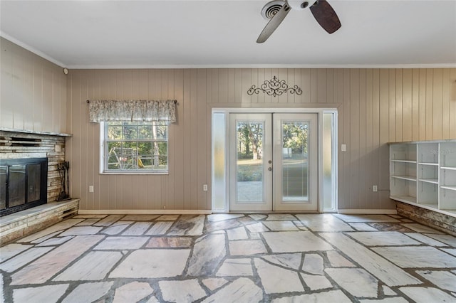 doorway with a fireplace, french doors, a wealth of natural light, and wood walls