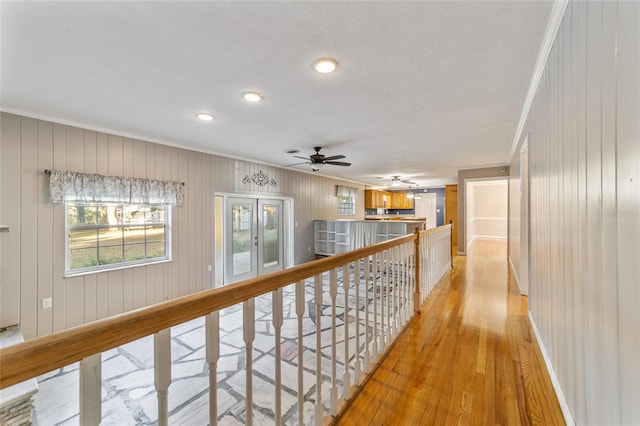 hallway with wood walls, light hardwood / wood-style floors, and crown molding