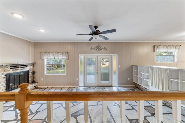 unfurnished living room featuring a fireplace, french doors, a wealth of natural light, and wooden walls