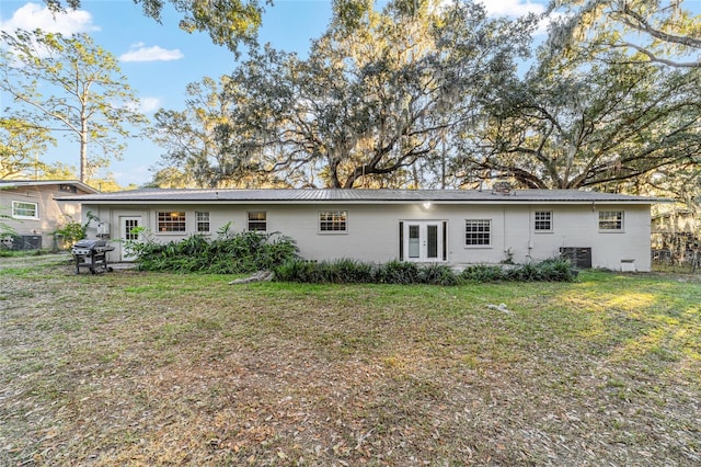 rear view of property featuring a lawn and french doors