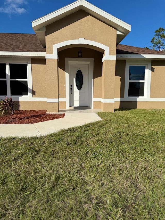 view of exterior entry with a yard