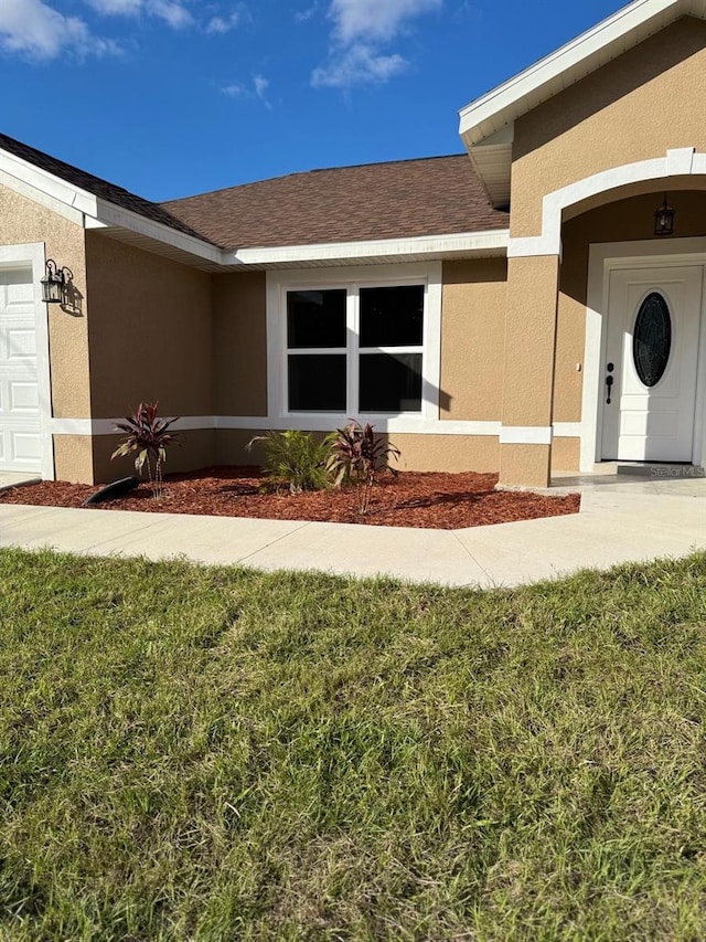 view of exterior entry with a yard and a garage