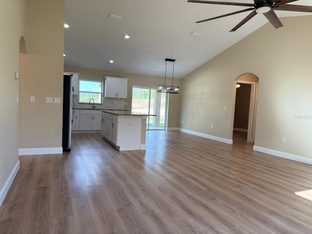 kitchen with light wood-type flooring, pendant lighting, white cabinetry, a kitchen island, and stainless steel refrigerator