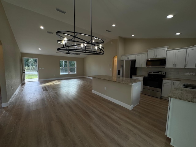 kitchen featuring stainless steel appliances, decorative light fixtures, hardwood / wood-style flooring, white cabinets, and lofted ceiling