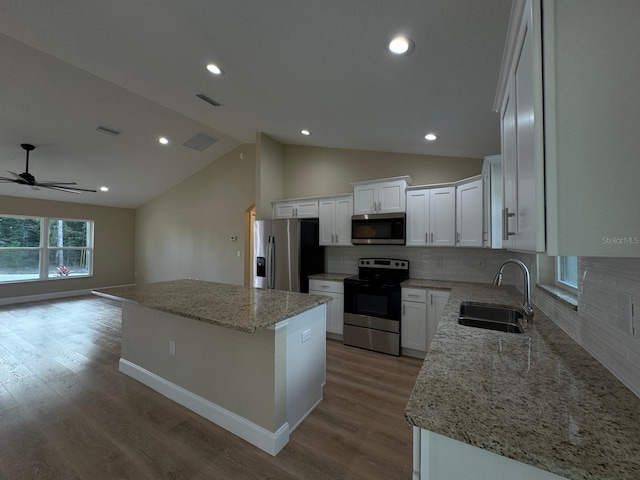 kitchen featuring a center island, lofted ceiling, white cabinets, sink, and appliances with stainless steel finishes