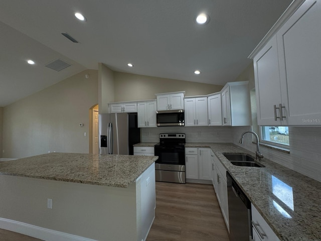 kitchen with white cabinets, lofted ceiling, sink, and appliances with stainless steel finishes