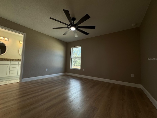 unfurnished bedroom with a textured ceiling, dark hardwood / wood-style flooring, ensuite bath, and ceiling fan