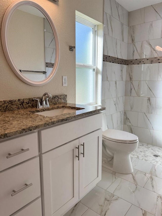 bathroom featuring tiled shower, vanity, and toilet