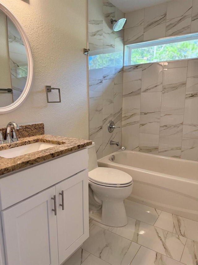 full bathroom featuring vanity, tiled shower / bath combo, and toilet