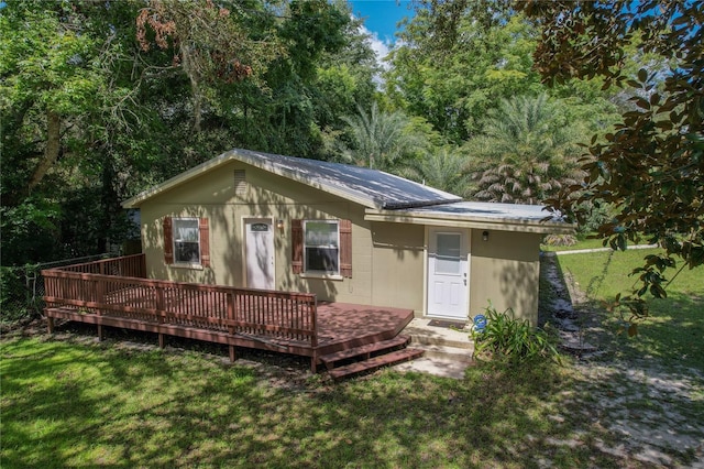 rear view of property featuring a deck and a yard