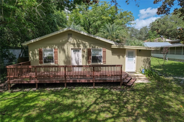 back of house featuring a deck and a lawn