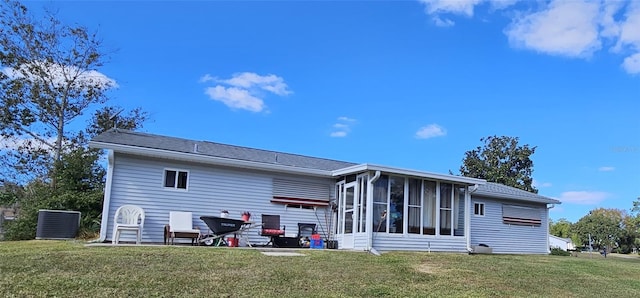 rear view of property featuring a sunroom, a lawn, and a patio area