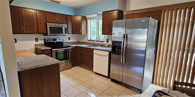 kitchen with decorative backsplash, appliances with stainless steel finishes, dark brown cabinets, sink, and light tile patterned floors