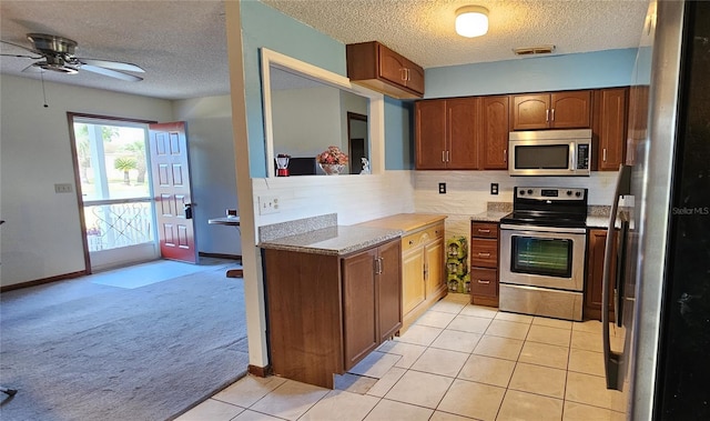 kitchen featuring a textured ceiling, stainless steel appliances, light carpet, and backsplash