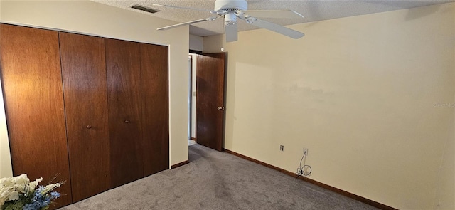 unfurnished bedroom with a closet, ceiling fan, carpet flooring, and a textured ceiling