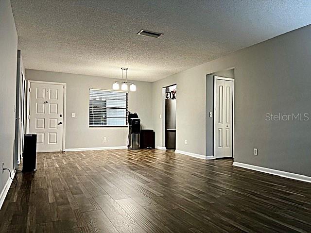 spare room featuring dark hardwood / wood-style floors, a textured ceiling, and a chandelier