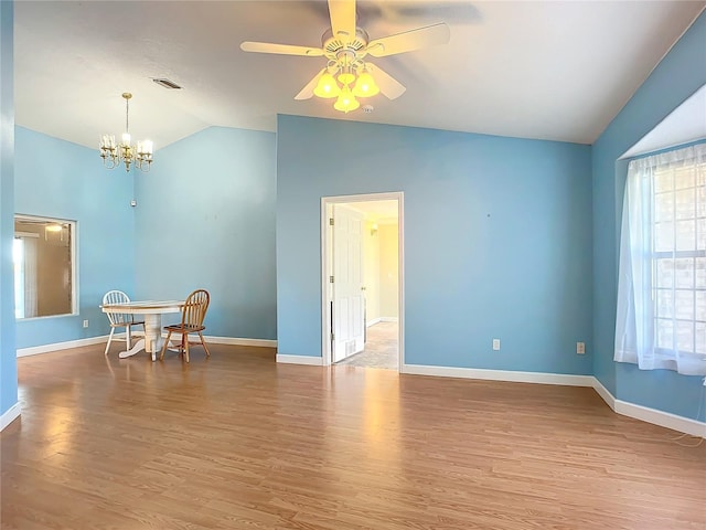 spare room with hardwood / wood-style flooring, ceiling fan with notable chandelier, and lofted ceiling