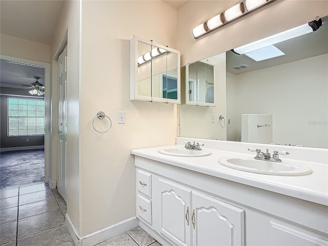 bathroom with a skylight, ceiling fan, tile patterned flooring, and vanity