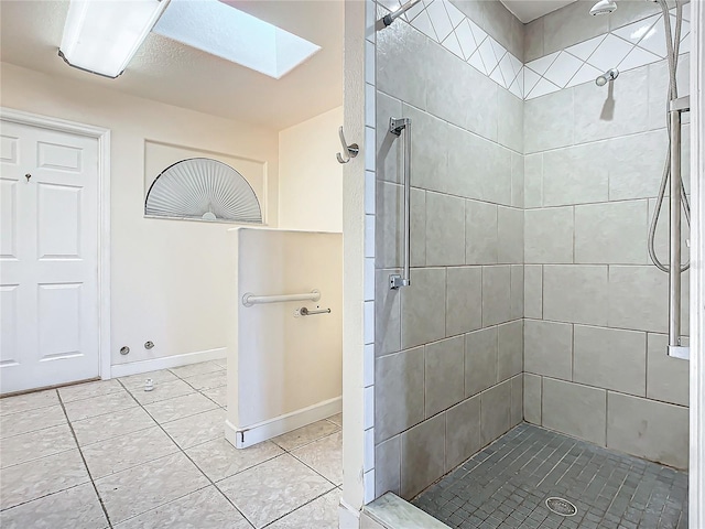 bathroom featuring tile patterned flooring, a tile shower, and a skylight