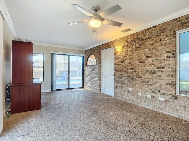 empty room featuring carpet flooring, crown molding, ceiling fan, and brick wall