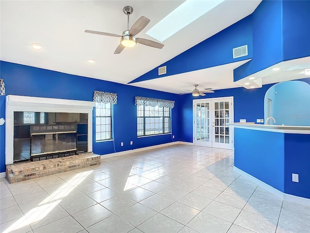 unfurnished living room with ceiling fan, light tile patterned floors, high vaulted ceiling, and french doors