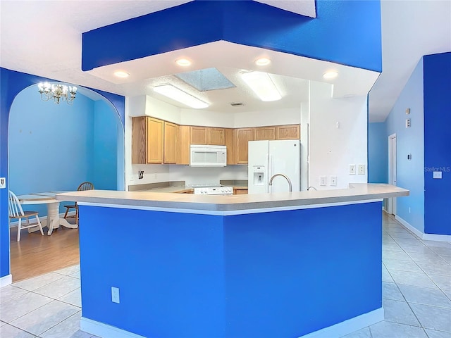 kitchen with kitchen peninsula, light tile patterned flooring, a chandelier, and white appliances