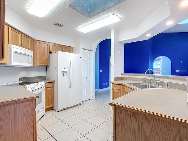 kitchen featuring kitchen peninsula, a textured ceiling, white appliances, sink, and light tile patterned floors