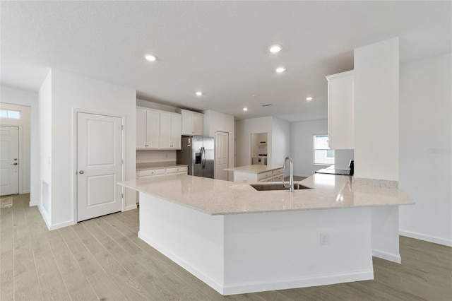 7930 SW 74th Loop, Ocala, FL 34481 - kitchen featuring stainless steel fridge, a sink, light wood finished floors, white cabinetry, and baseboards